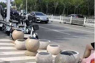 日照一海水浴场门口隔离石墩被涂抹沥青,游客带娃经过鞋和身上都粘上